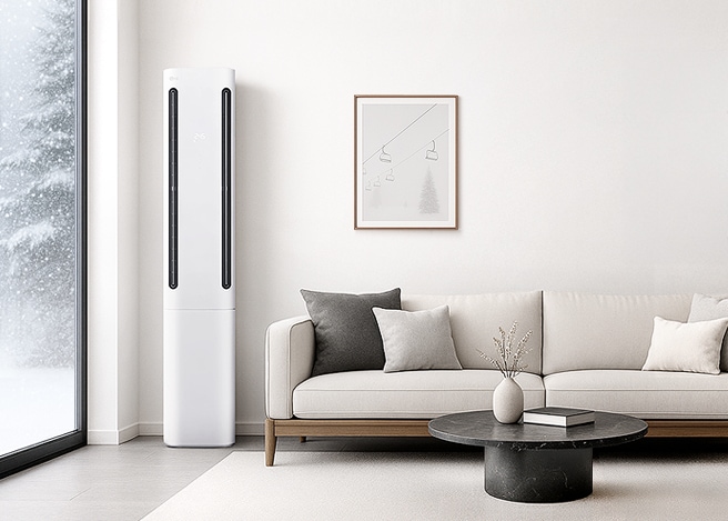 겨울 풍경이 보이는 거실에 흰색 LG 휘센 쿨 에어컨과 베이지색 소파, 원형 테이블이 놓인 따뜻한 인테리어 공간.